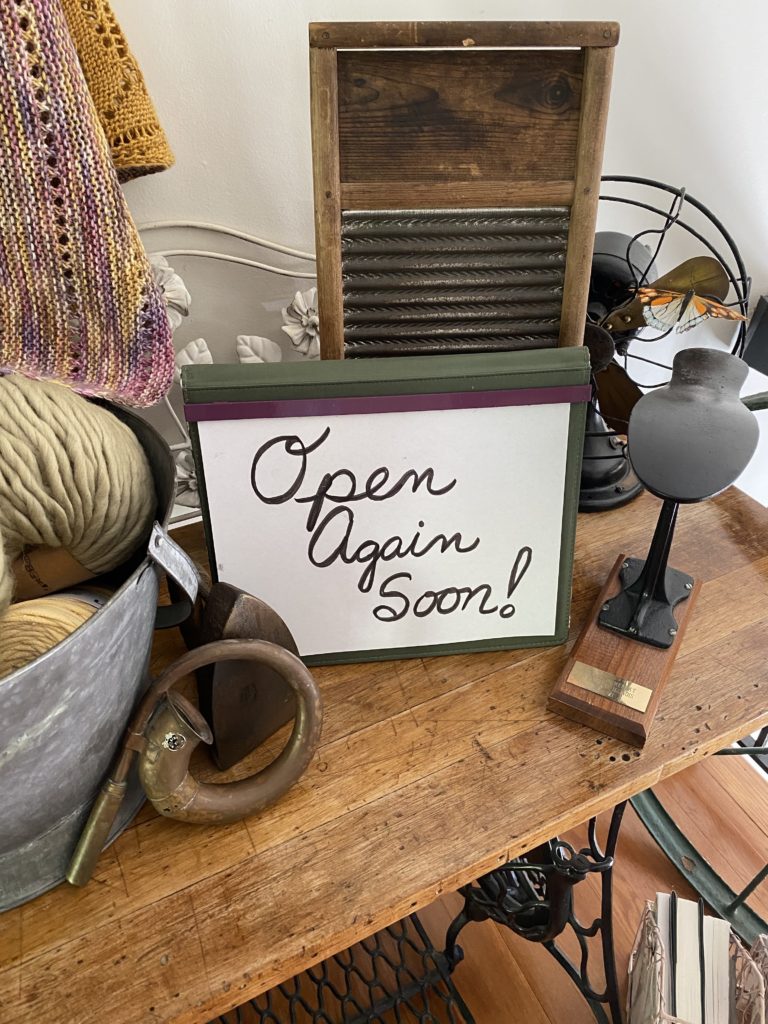 Antique shop table with "Open Again Soon!" sign
